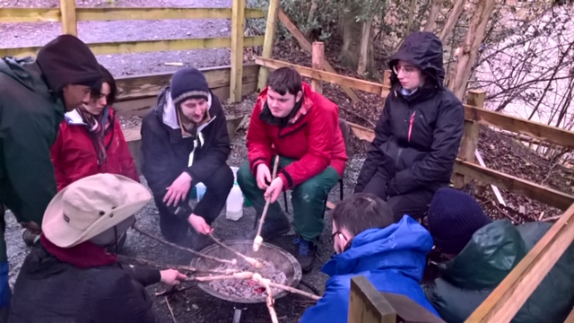 Group of students round camp fire
