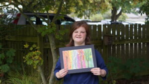 Isabelle stood in the college gardens holding her winning artwork