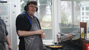 James stood in front of a cooker making a frying pan of chicken noodles